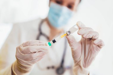 Doktor aşı ve şırınga tutuyor. Önleme ve aşılama için kullanılır..