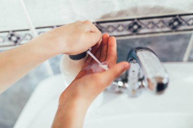 Çocuk banyoda ellerini yıkıyor. Virüs ve bakterilere karşı koruma. Kapat..