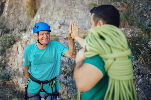 Senior man with a rope preparing for climbing on the rock.