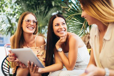 Dijital tablet kullanarak ve eğlenmek bir kafede üç güzel arkadaş