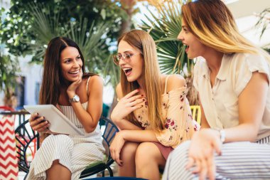 Dijital tablet kullanarak ve eğlenmek bir kafede üç güzel arkadaş