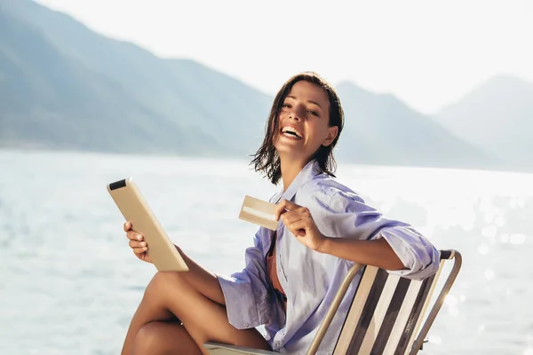 Mujer Sonriente Sentada Tumbona Junto Mar Usando Tableta Tarjeta Crédito — Foto de Stock