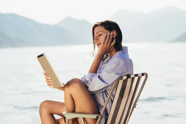 Lachende Vrouw Zittend Ligstoel Aan Zee Met Behulp Van Tablet — Stockfoto