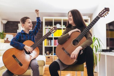 Erkek ve kız kardeş evde gitar çalıp eğleniyorlar..