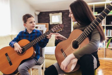 Erkek ve kız kardeş evde gitar çalıp eğleniyorlar..