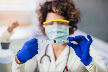 Doktor şırıngayı aşı için hazırlar..