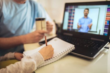 Öğrenci çocuk internetten eğitim veriyor. Baba, oğluna ev ödevinde yardım ediyor. Evde dizüstü bilgisayar öğretmeniyle video konferansında.. 