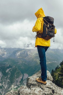 Orta yaşlı yağmurluk ve sırt çantalı gezgin dağların keyfini çıkarıyor..