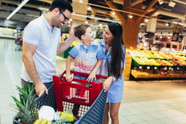 Çocuklu ve alışveriş arabalı mutlu bir aile marketten ya da marketten yiyecek alıyor.