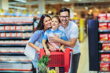 Çocuklu ve alışveriş arabalı mutlu bir aile marketten ya da marketten yiyecek alıyor.