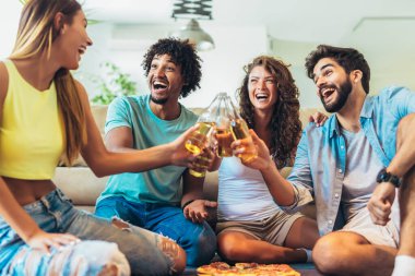 Bir grup etnik kökenli genç arkadaş evde pizza yiyor ve eğleniyorlar..