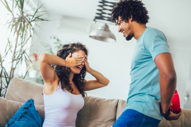 Gülümseyen adam evde hediyesiyle kız arkadaşına sürpriz yapıyor..