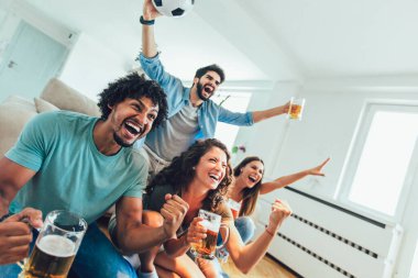 Çok heyecanlı arkadaşlar evde yemek yiyerek ve futbol maçı izleyerek eğleniyorlar. Arkadaşlık, kira, dinlenme, ev partisi konsepti.