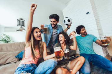 Çok heyecanlı arkadaşlar evde yemek yiyerek ve futbol maçı izleyerek eğleniyorlar. Arkadaşlık, kira, dinlenme, ev partisi konsepti.