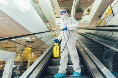 Tehlikeli madde giysileri içinde profesyonel işçiler alışveriş merkezinin iç kısımlarını dezenfekte ediyor, salgın hastalık riski, koronavirüs...
