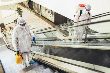 Tehlikeli madde giysileri içinde profesyonel işçiler alışveriş merkezinin iç kısımlarını dezenfekte ediyor, salgın hastalık riski, koronavirüs...
