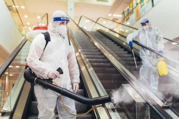 Profesjonalni Pracownicy Kombinezonach Ochronnych Dezynfekujących Wnętrze Centrum Handlowego Pandemiczne Zagrożenie — Zdjęcie stockowe