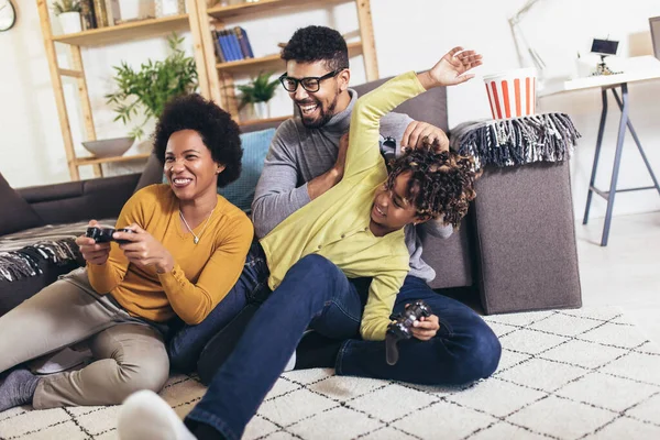 African American family at home sitting in sofa couch and playing console video games together