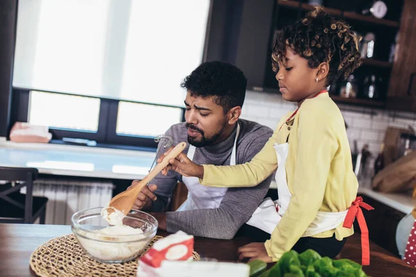 Dad and daughter baking together in the kitchen.