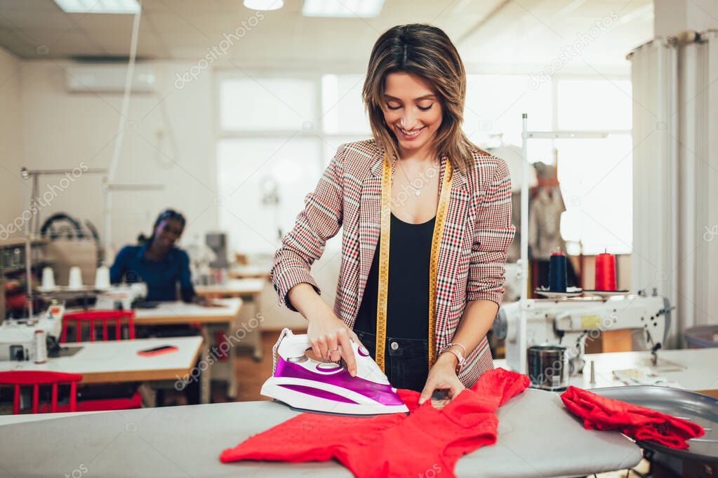 Tailor ironing in the modern sewing workshop. 