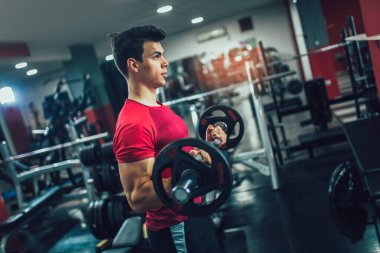 Spor salonunda egzersiz yapan yakışıklı bir genç.