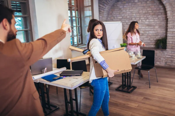 İş kadını bütün kişisel eşyalarını ve dosyalarını modern ofiste istifa etmek için kahverengi karton bir kutuya koyuyor..