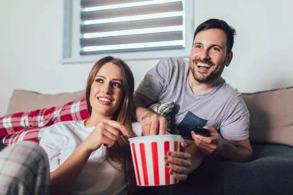 カップルで愛に座っていますリビングルームソファ テレビを見て ポップコーンを食べる — ストック写真