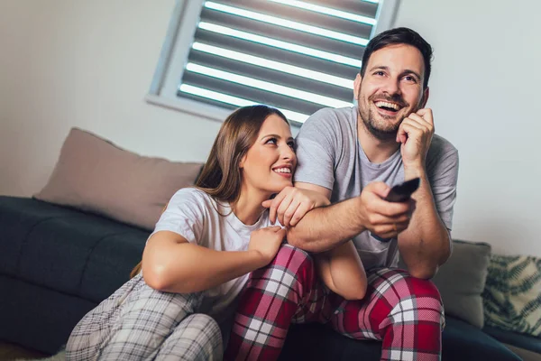 Couple in love sitting on a living room sofa, watching TV