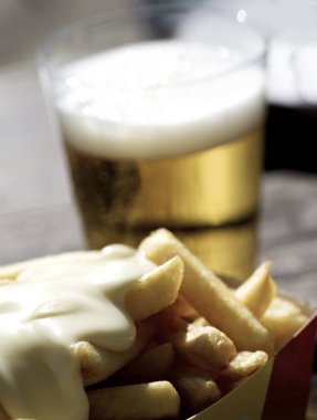 Lezzetli patates kızartması. Peynir soslu. Bulanık bir bardak bira.