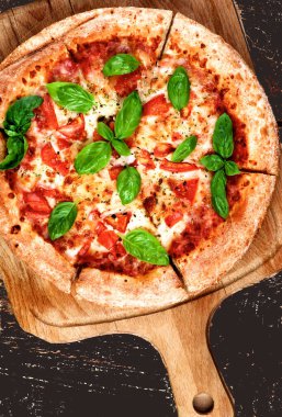 Domatesli taze Margarita Pizza, Peynir ve Basil Leafs kesim tahtasında. Koyu arkaplanda Üst Görünüm