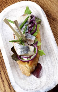 Salamura edilmiş sardalya, kırmızı soğan ve ahşap tabakta yakın plan İspanyol Tapas 'ı. Üst Görünüm