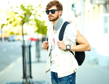 Funny smiling hipster handsome man in stylish summer clothes posing on street background 