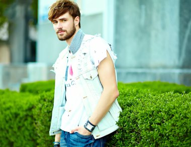 Funny smiling hipster handsome man in stylish summer clothes posing on street background 