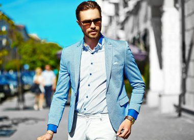 Yüksek moda bakmak. Takım elbise li genç şık, mutlu yakışıklı işadamı modeli güneş gözlüğü ile sokakta yürüyor