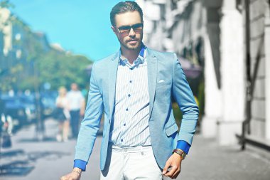 Yüksek moda bakmak. Takım elbise li genç şık, mutlu yakışıklı işadamı modeli güneş gözlüğü ile sokakta yürüyor