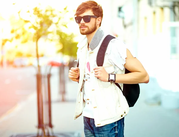 Funny smiling hipster handsome man in stylish summer clothes posing on street background 