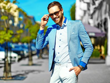 Yüksek moda bakmak. Takım elbise li genç şık, mutlu yakışıklı işadamı modeli güneş gözlüğü ile sokakta yürüyor