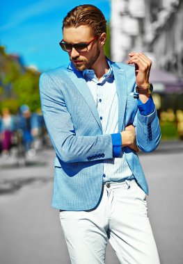 Yüksek moda bakmak. Takım elbise li genç şık, mutlu yakışıklı işadamı modeli güneş gözlüğü ile sokakta yürüyor