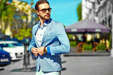 Yüksek moda bakmak. Takım elbise li genç şık, mutlu yakışıklı işadamı modeli güneş gözlüğü ile sokakta yürüyor
