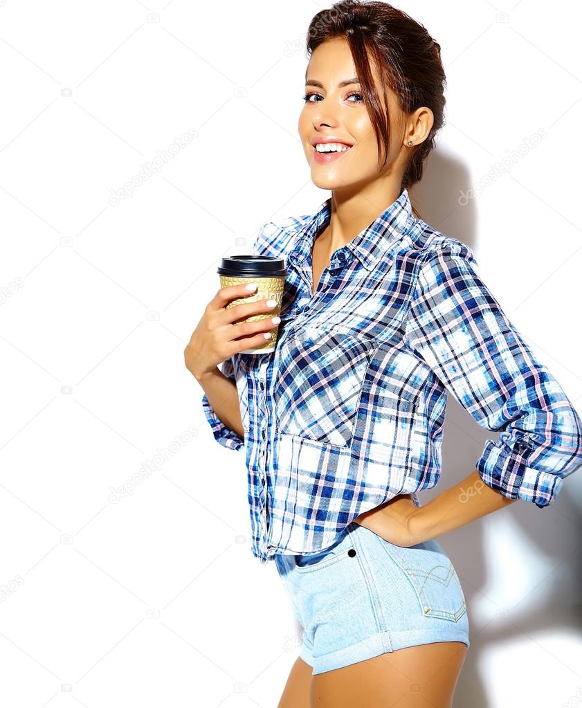 Portrait of beautiful stylish cool funny teenage girl going crazy in checkered shirt, holding plastic coffee cup