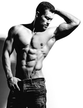 Güçlü sağlıklı yakışıklı atletik erkek Fitness Model beyaz duvara yakın poz portresi