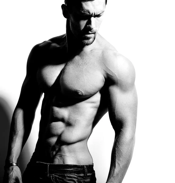 Güçlü sağlıklı yakışıklı atletik erkek Fitness Model beyaz duvara yakın poz portresi