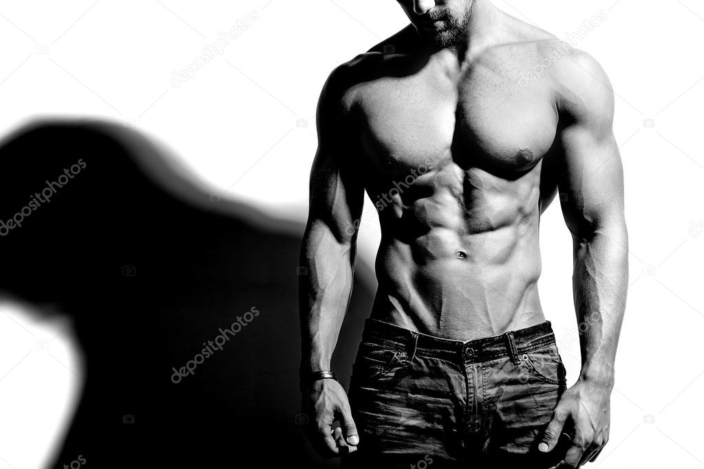 Portrait of strong healthy handsome Athletic Man Fitness Model posing near white wall