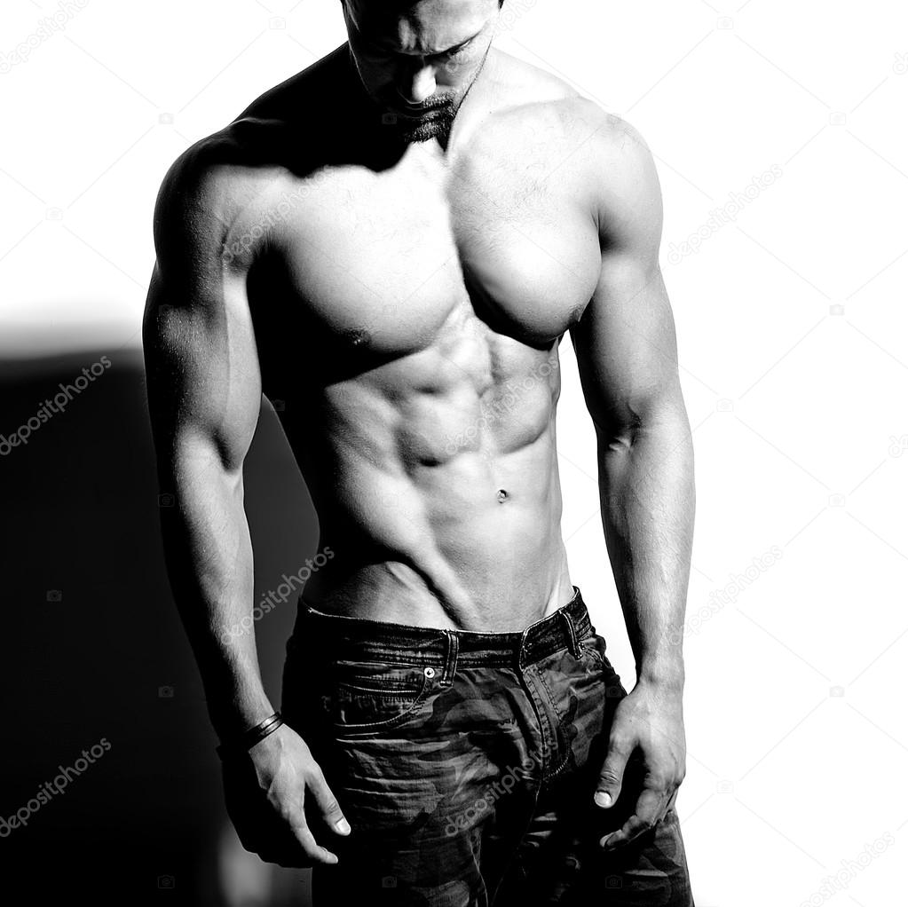 Portrait of strong healthy handsome Athletic Man Fitness Model posing near white wall