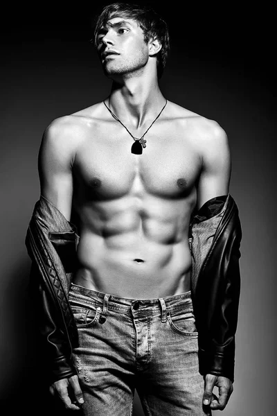 Karın kasları deri ceketle gösterilen Studio poz kaslı fit erkek model adam