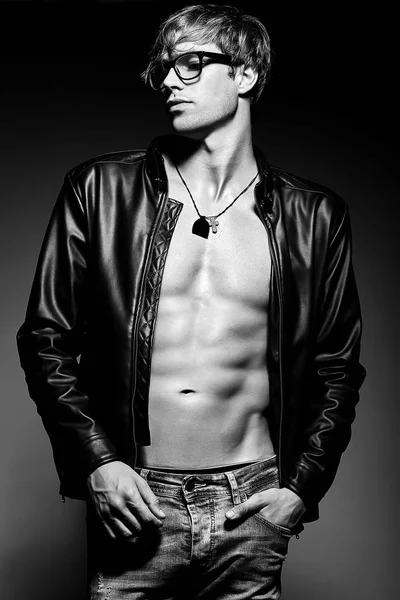 Muscled fit male model man posing in studio showing his abdominal muscles in  leather jacket — Stock Photo, Image