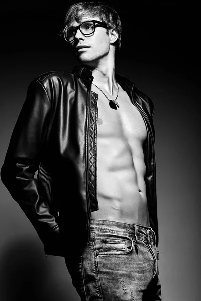 Muscled fit male model man posing in studio showing his abdominal muscles in  leather jacket — Stock Photo, Image