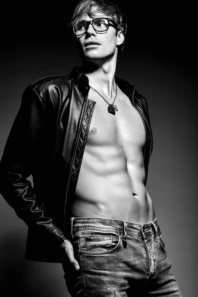 Muscled fit male model man posing in studio showing his abdominal muscles in  leather jacket — Stock Photo, Image