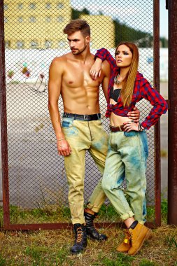 Seksi şık sarışın genç kadın modeli ile mükemmel parlak makyaj ile cilt sunbathed ve yakışıklı kaslı adam açık havada Jeans