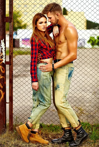 Сексуальная стильная молодая модель с ярким макияжем с идеальной солнечной кожей и красивым мускулистым мужчиной в джинсах на улице — стоковое фото